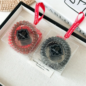 Détail d'élastiques spirales rouges et noirs dans une boîte cadeau avec ruban décoratif
