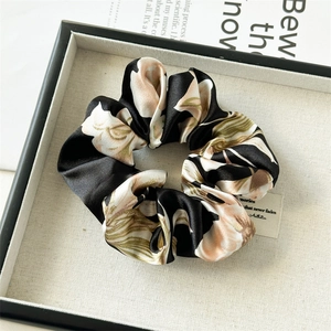 Macro detail of satin floral scrunchie with soft fabric folds and branded woven label