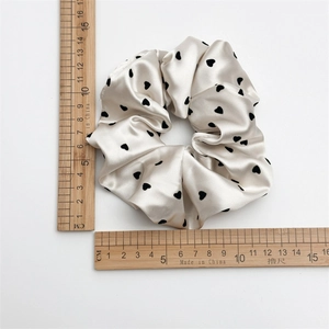 Elegant cream satin scrunchie with black heart patterns measuring 10.5cm in diameter