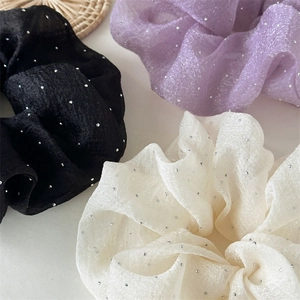 Détail de chouchous en tulle noir, lilas et crème avec des strass argentés brillants