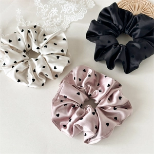 Elegant satin hair scrunchies with flocked heart patterns in white, pink, and black colors
