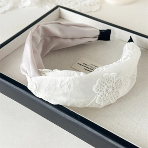 Gros plan sur le serre-tête torsadé en satin rose avec broderies florales élégantes
