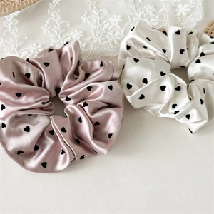 Close-up of pink and cream satin heart print scrunchies with soft pleated texture