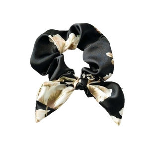 Floral satin hair scrunchie in black with large beige flower pattern and elegant bow ribbon