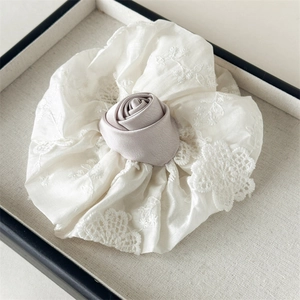 Détail du chouchou en dentelle blanche avec une rose en soie rose élégante