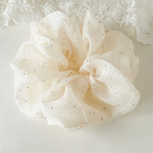 Gros plan sur chouchou en organza crème orné de strass argentés et texture de maille fine