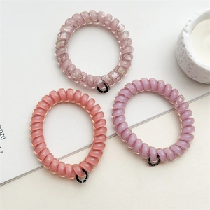 Détail de trois élastiques spirale en rose et lavande avec petites étiquettes noires