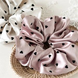 Close-up of elegant white and pink heart print satin scrunchies on a tray