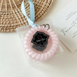 Élastique à cheveux spirale rose dans une boîte cadeau avec un ruban bleu clair