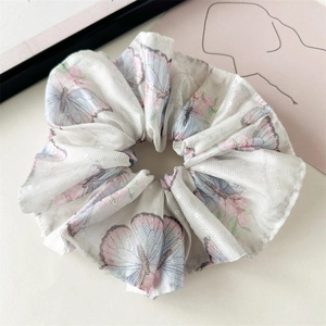 Détail d'un chouchou blanc avec papillons violets et paillettes scintillantes