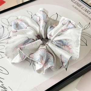 Détail du chouchou en mousseline blanche avec motifs papillons et paillettes brillantes