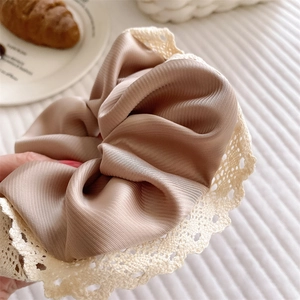 Detailaufnahme champagnerfarbenes Satin-Haargummi mit Plissee und Spitzenkante