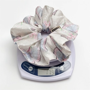 Chouchou papillon en satin à paillettes sur balance montrant un poids léger de 17,9g