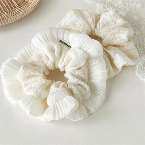 Détail de l'élastique à cheveux crème en lin brodé avec dentelle et étiquette tissée