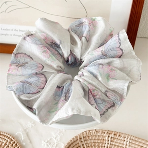 Détail d'un chouchou en maille blanche avec imprimé papillon élégant sur base céramique