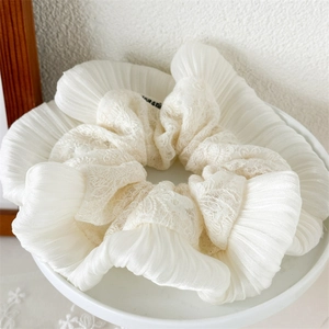 Détail d'un chouchou en coton et lin crème avec broderie en dentelle et textures plissées