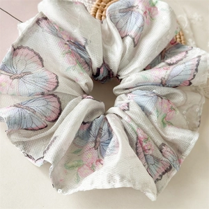Vue macro d'un chouchou large en organza avec motifs papillons et paillettes argentées