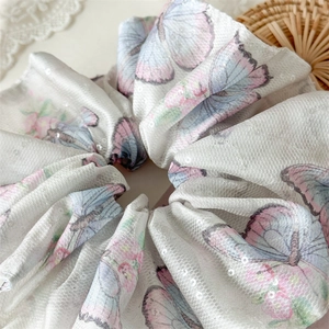Détail d'un chouchou papillon violet à paillettes avec un élégant tissu en satin plissé