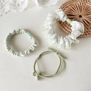 Detailset van drie zeer elastische groene bloemen-scrunchies en haarelastiekjes met parels