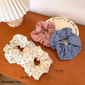 Détail de chouchous à fleurs montrant le diamètre d'étirement de 6cm à 15cm et le tissu