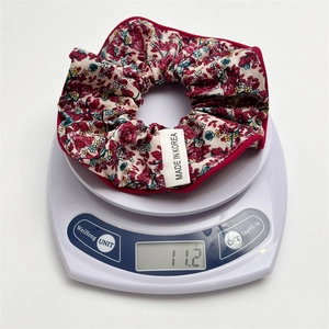 Chouchou à fleurs pesant 11,2g sur balance blanche avec étiquette Fabriqué en Corée