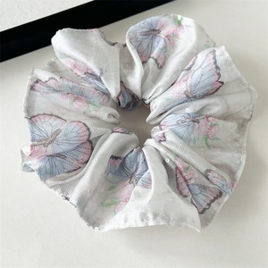 Détail macro du grand chouchou en satin avec motif papillon et paillettes scintillantes