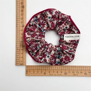 Chouchou à fleurs avec bords rouges et diamètre de 14cm montré avec une règle