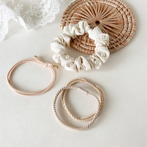 Gedetailleerde set met witte parelscrunchie, roze haarelastiek en beige banden op kant