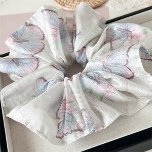 Gros plan détaillé du grand chouchou à motif papillon violet en tissu satiné