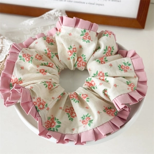 Detailaufnahme eines floralen XXL-Haargummis mit rosa Rüschen auf einem Keramikteller