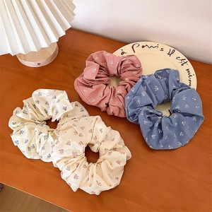 Lot de chouchous à fleurs roses, bleus et crème sur une table en bois vintage