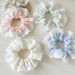 Detailed shot of pastel lace scrunchies with floral embroidery in pink and mint colors