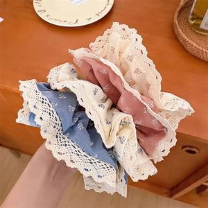 Détail de trois chouchous à fleurs avec bordure en dentelle blanche en bleu, beige et rose
