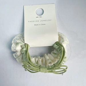 Detail van bloemen kant haarelastiekje met groene elastische strik op presentatiekaart
