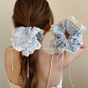 Detail view of blue plaid scrunchie with white lace trim and ribbon bow on model hair