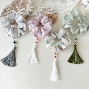 Close-up of ink floral scrunchies with long silk tassels and decorative bead accents
