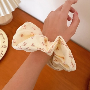Chouchou à fleurs avec bords en dentelle porté au poignet dans un décor chaleureux