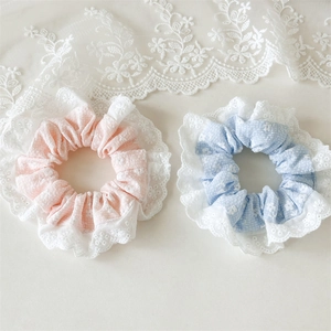Detailed view of floral scrunchies with white lace edges in pink and light blue