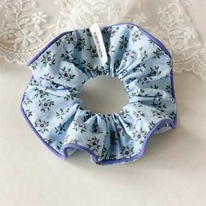 Détail d'un chouchou floral avec bords violets et étiquette en tissu fait main