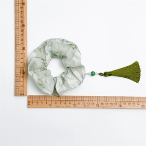 Detail showing light green floral scrunchie with dark green tassel and dimensions on scale