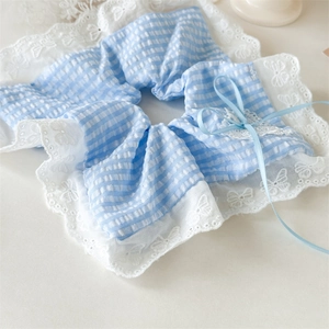 Close-up of blue plaid scrunchie with white lace trim and a delicate silk ribbon bow