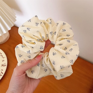 Gros plan du chouchou en tissu beige à motif floral avec bordure en dentelle élégante
