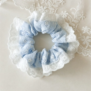 Detailed shot of light blue floral scrunchie featuring delicate white lace embroidery