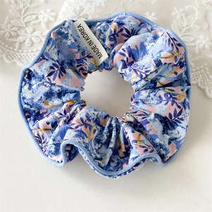 Détail d'un chouchou floral avec bordure bleue et étiquette Made in Korea incluse