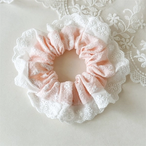 Close-up of pink floral scrunchie with intricate white lace embroidery details