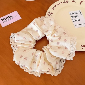 Détail d'un chouchou à fleurs avec bordure en dentelle sur fond de bois chaud