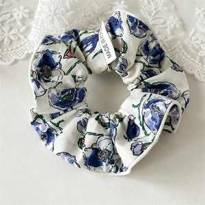 Détail d'un chouchou floral avec fleurs bleu violet et étiquette Made in Korea