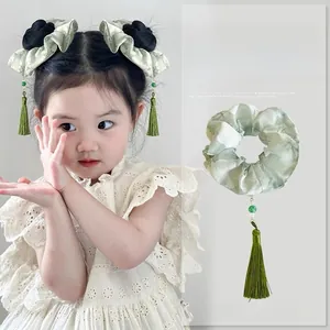 Detail of light green ink-wash fabric scrunchie with long silk tassels and green beads