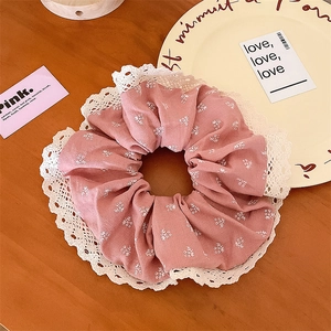 Vue détaillée du chouchou rose à fleurs avec dentelle délicate et texture de tissu doux
