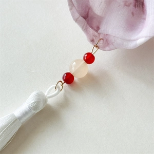 Detail of silk tassel and beaded charm attached to floral fabric scrunchie